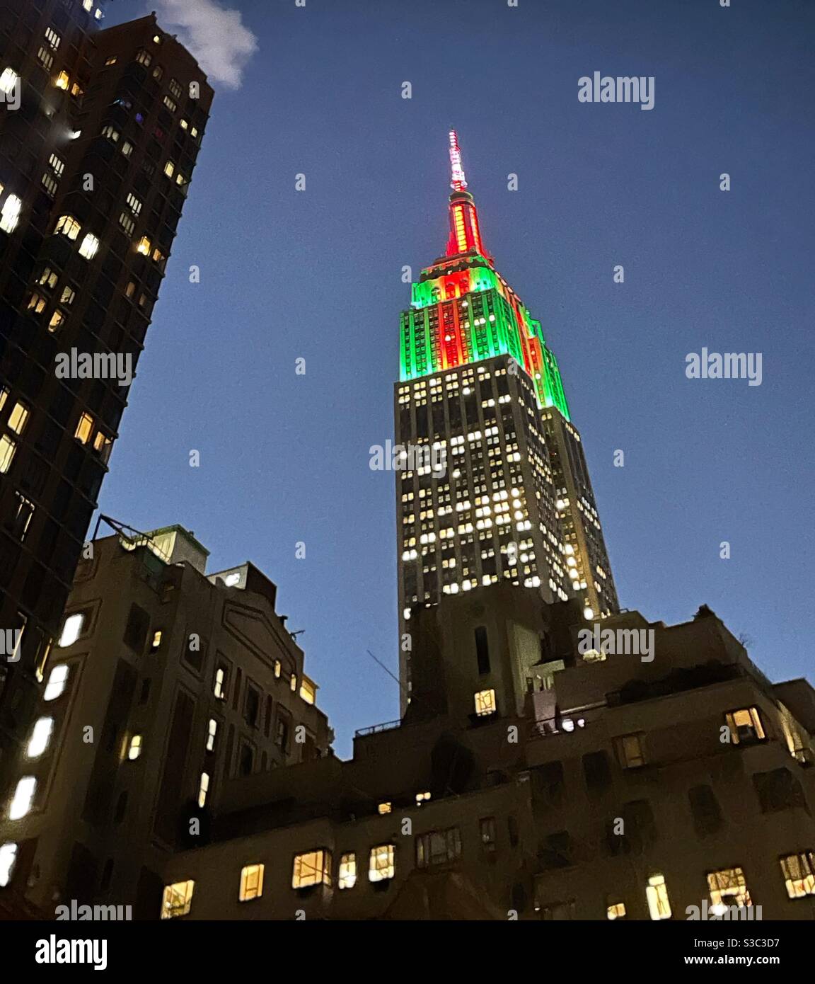 Blick in die Dämmerung auf das Empire State Building mit weihnachtlicher Beleuchtung von der Park Avenue an der Ostseite Manhattans während der Weihnachtszeit. - Smartphone-aufgenommenes Stockfoto
