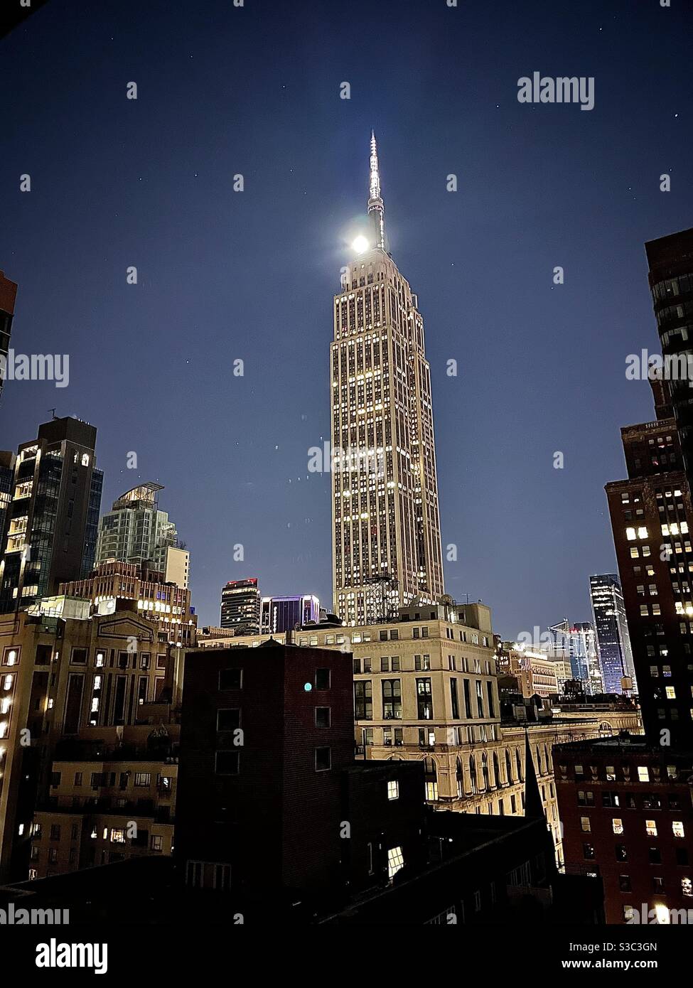 Der Moment, bevor ein Vollmond hinter dem Empire State Building eintaucht, wird in einem 3-Uhr-Bild festgehalten. Stockfoto