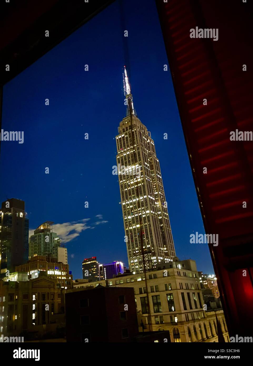 Nachtansicht des Empire State Building von einem Hochhaus Fenster in Midtown Manhattan - Smartphone-aufgenommenes Stockfoto