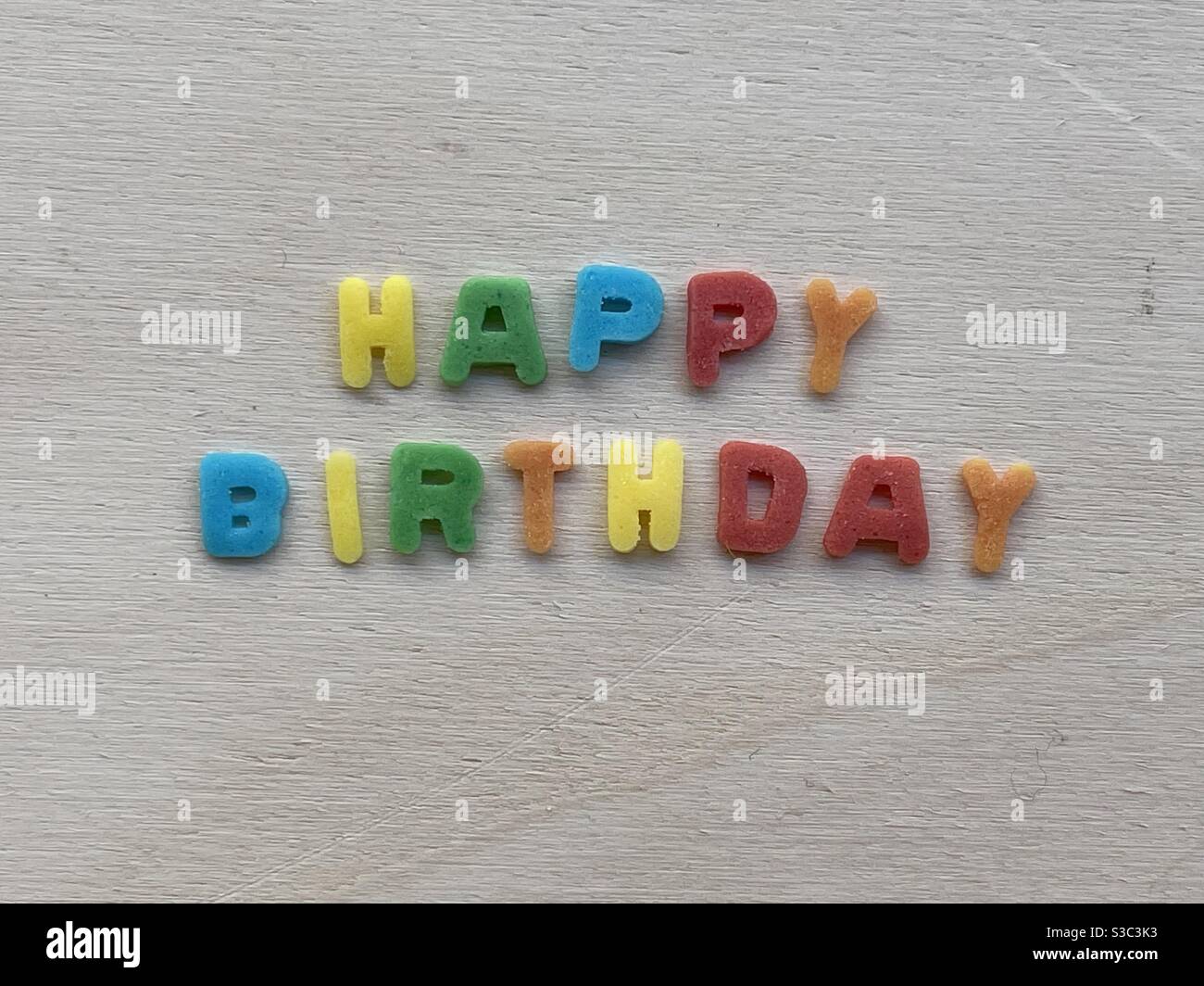 Happy Birthday Text mit farbigen Zucker ornamentalen Buchstaben über komponiert Ein bekommertes Brett Stockfoto