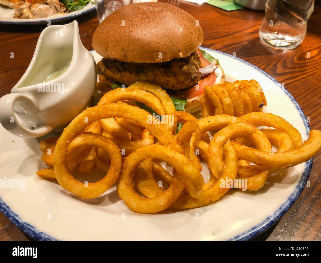 Ein Pub Lunch bestehend aus Burger und lockigen Pommes. Stockfoto