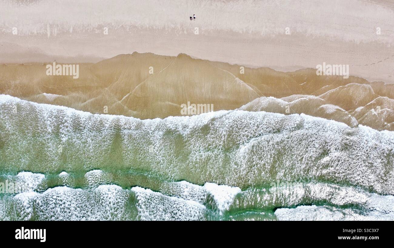 Luftdrohne Aufnahme von brechenden Wellen auf dem Sand Strand bei Woolacombe Nord Devon im Sommer 2020 mit zwei Erwachsene isoliert am einsamen Strand Stockfoto