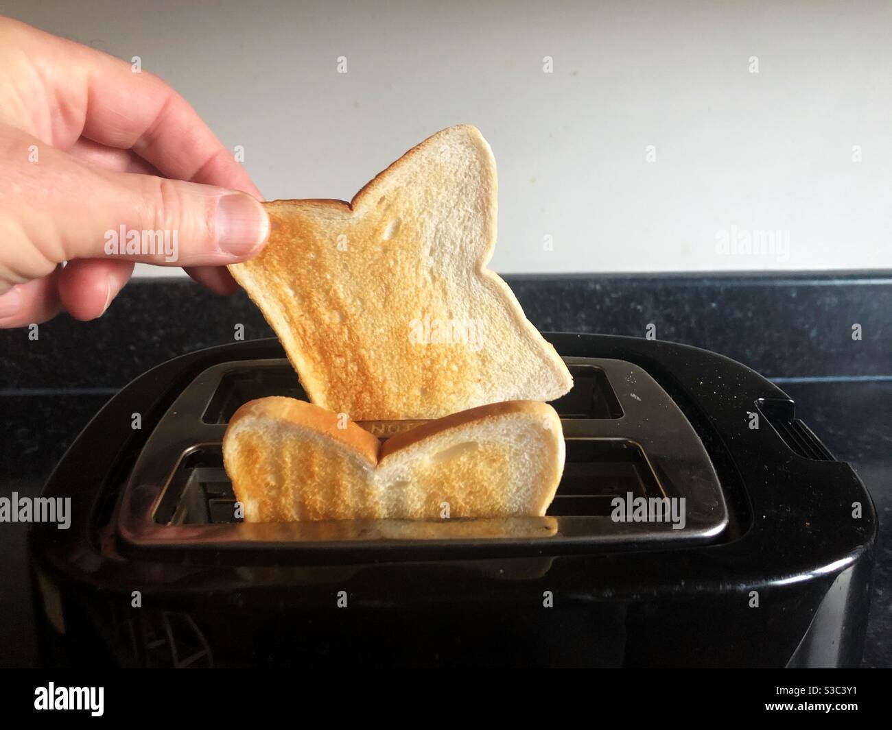 Toast aus dem Toaster nehmen - Smartphone-aufgenommenes Stockfoto