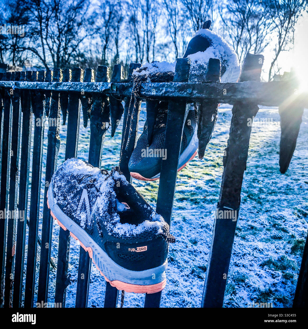 Ein Paar Trainer an einem Metallzaun gebunden Stockfoto