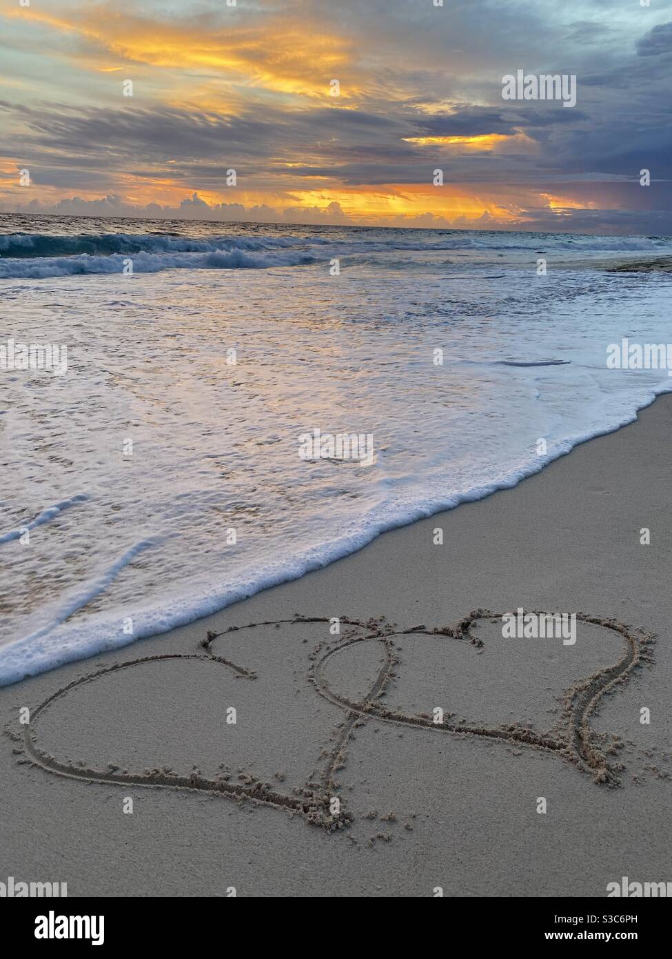 Sandzeichnung, aufgenommen mit einer Welle bei Sonnenuntergang Stockfoto