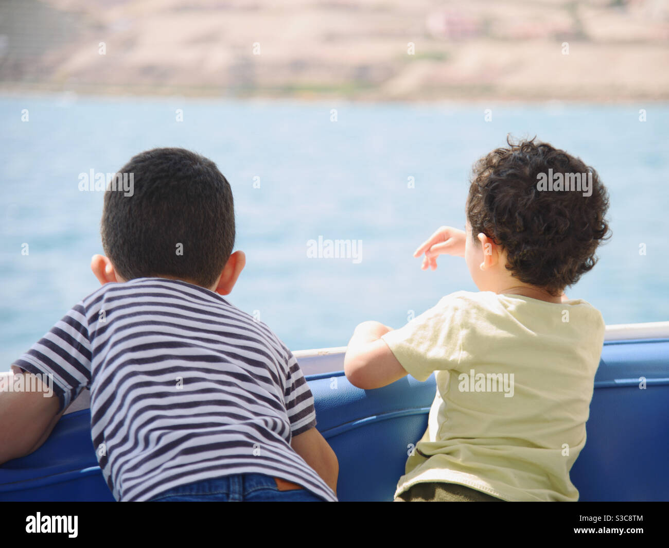 Zwei Kinder beobachten das Meerwasser von einem Boot aus Stockfoto