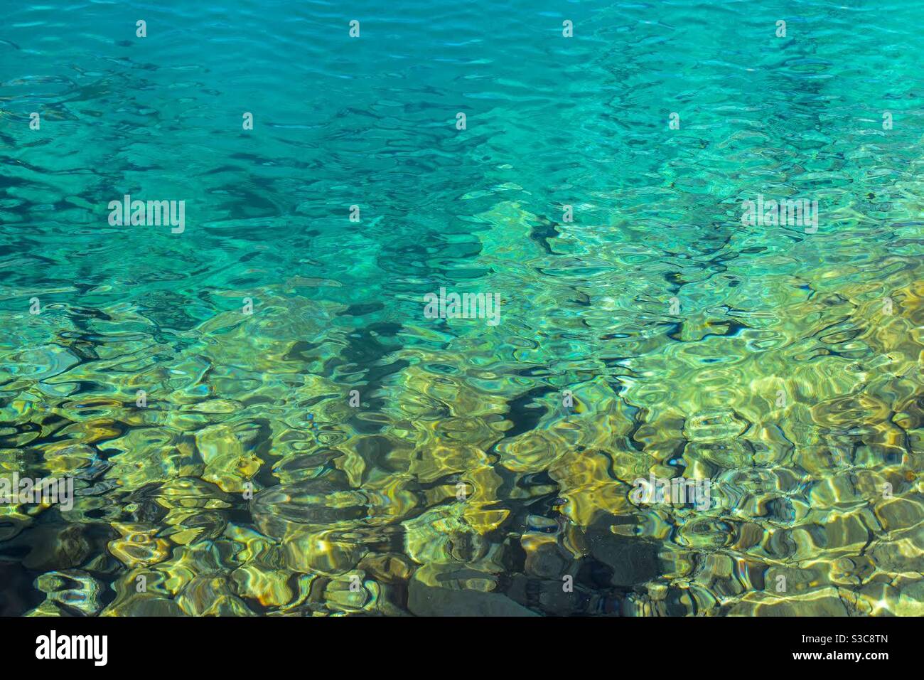 Welliges blaues Wasser und Felsen darunter Stockfoto