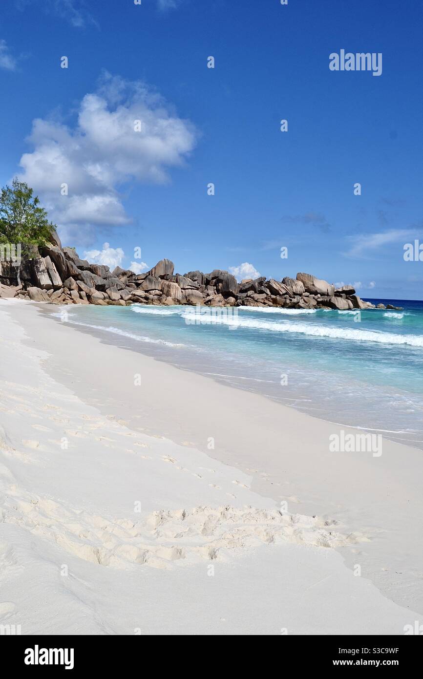 Magischer und idyllischer tropischer Strand im exotischen Paradies La digue mit Bäumen, Sand, Fußabdrücken, türkisfarbenem Meer und Felsbrocken auf den luxuriösen Seychellen bei strahlendem Sommersonnenschein. Stockfoto