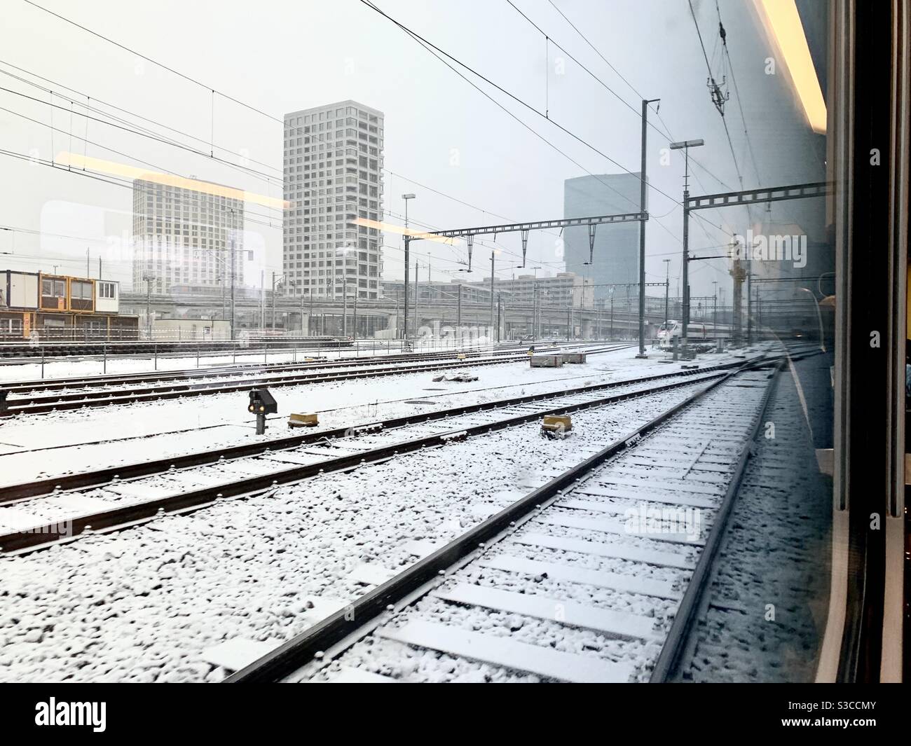 Bahnhof Hardbrücke in Zürich, Schweiz wie im Winter vom Zug aus beobachtet, unter Schneefall. Es gibt ein neues Wohn- und Geschäftsviertel. Stockfoto