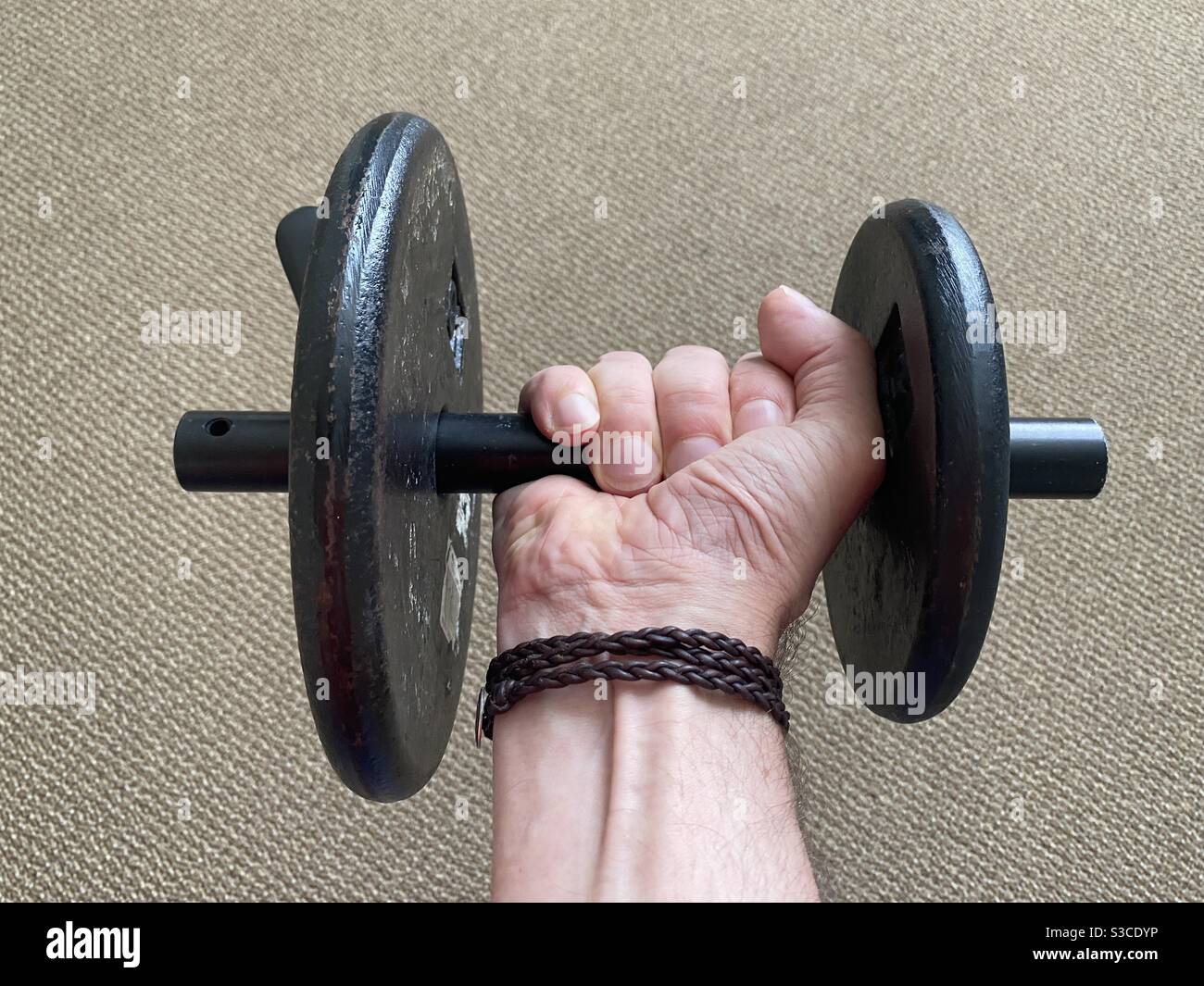 Hand des Mannes mit Lederarmband, heben eine falsch abgestimmte fünf und zehn Pfund Gewicht auf einem schwarzen Balken gesetzt Stockfoto