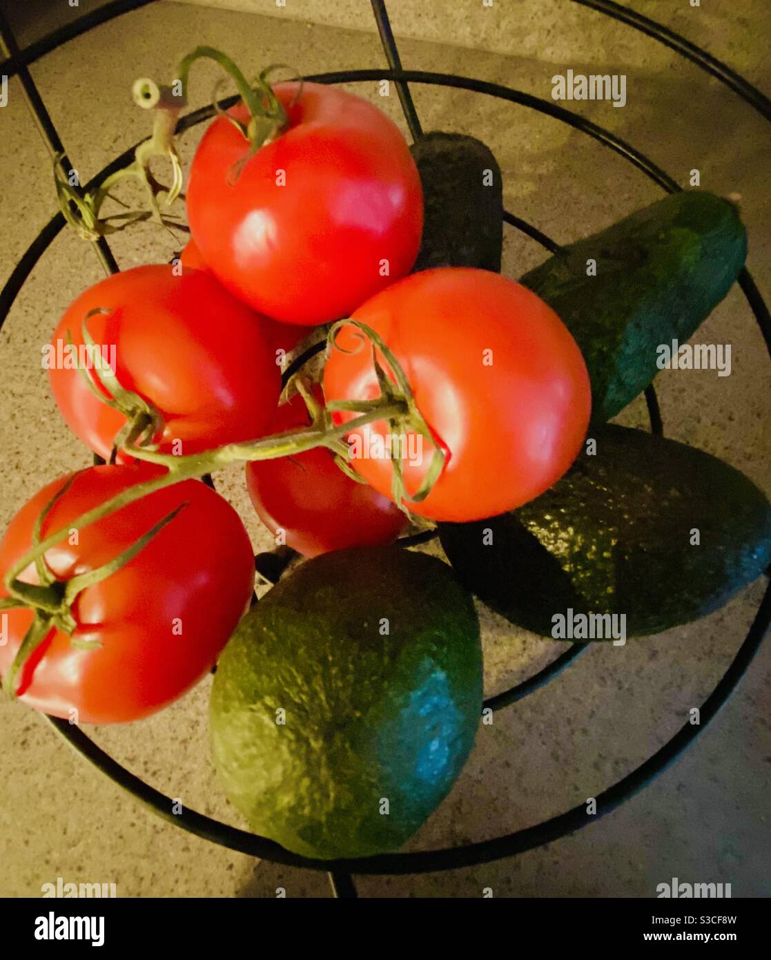 Avocados und Reben gereifte Tomaten in einem Metall-Obstbaum Stockfoto
