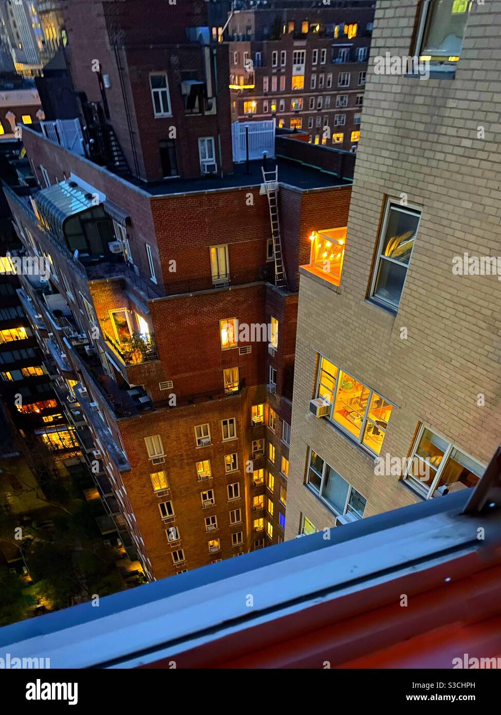 Ich spioniere...wie eine Szene aus dem Film Rear Window, schauen Sie durch ihre Fenster in das Leben der New Yorker, wie sie von diesem Park Avenue Fenster aus gesehen werden, das nachts zur 36. Straße in Manhattan, NY, USA, zeigt - Smartphone-aufgenommenes Stockfoto