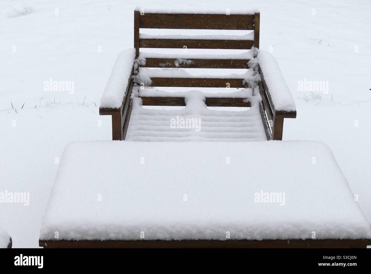 Nehmen Sie Platz im verschneiten Garten Stockfoto