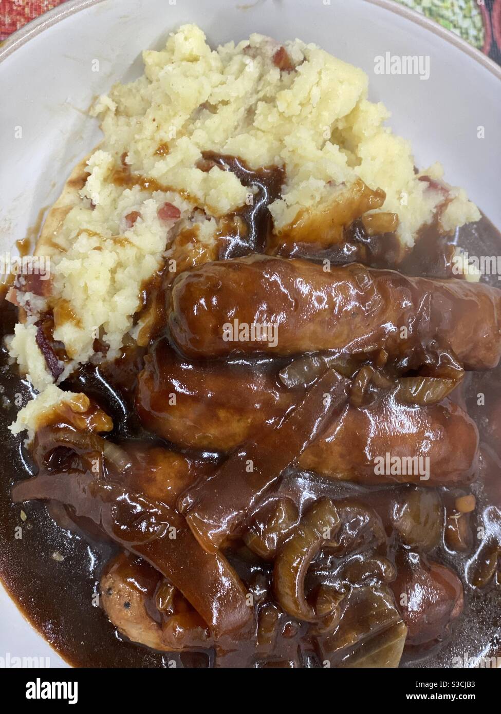 Cumberland Wurst, Bacon Mash und üppige Zwiebelsoße - Smartphone-aufgenommenes Stockfoto