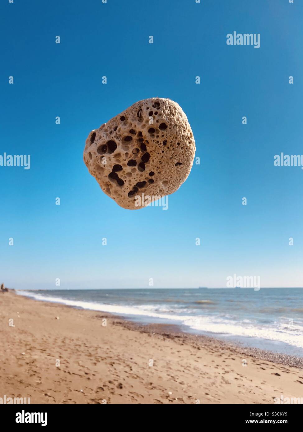 Felsen, der Loch auf ihm hat, schwebt in der Luft - Smartphone-aufgenommenes Stockfoto