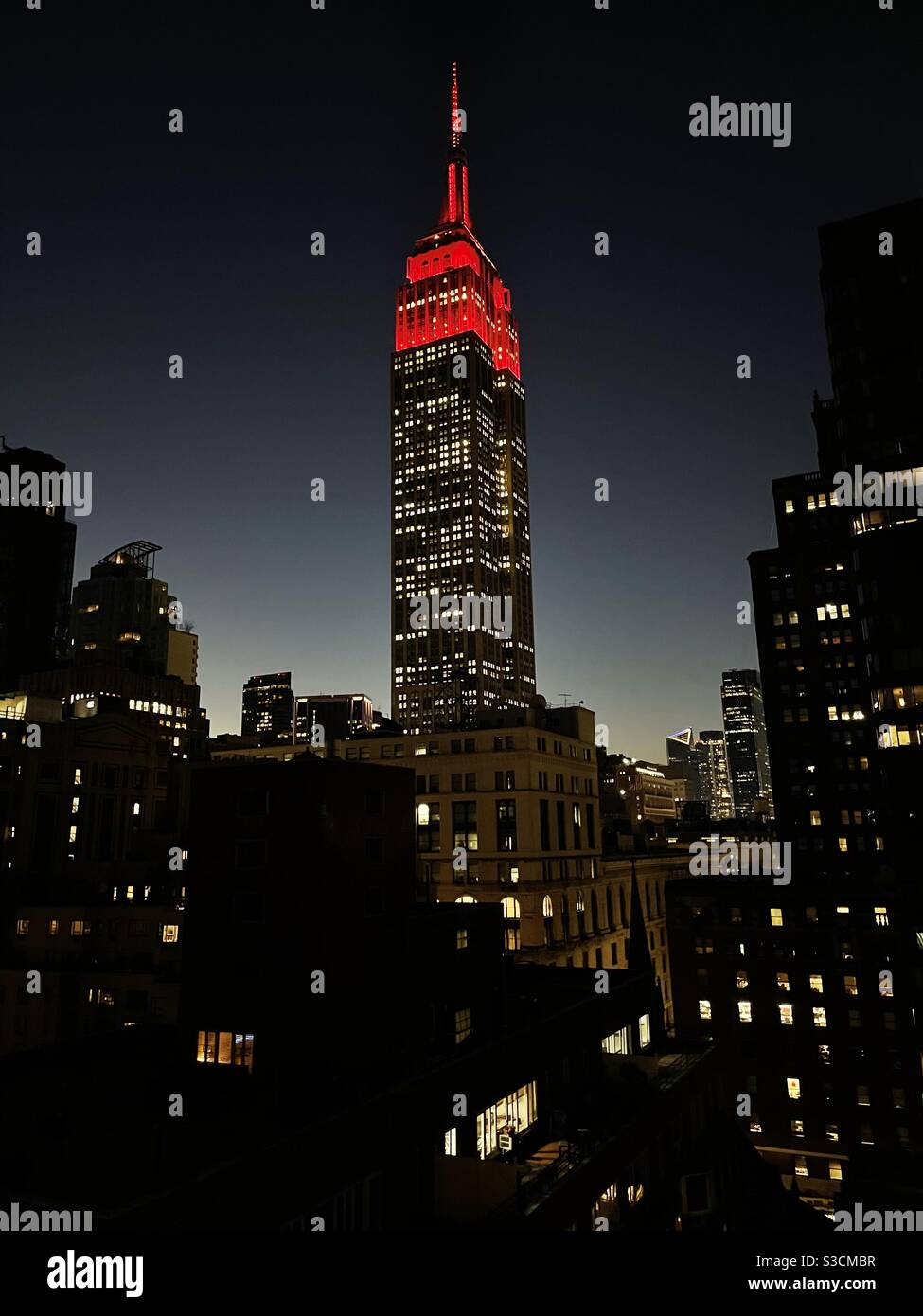 Leuchtend rote Lichter leuchten auf dem Empire State Building zu Ehren derer, die an dem Covid-Virus gestorben sind. Die Beleuchtung ändert sich jeden Abend, wie von Marc Brickman entworfen, der für seine Rock & Roll-Erfahrung bekannt war. - Smartphone-aufgenommenes Stockfoto