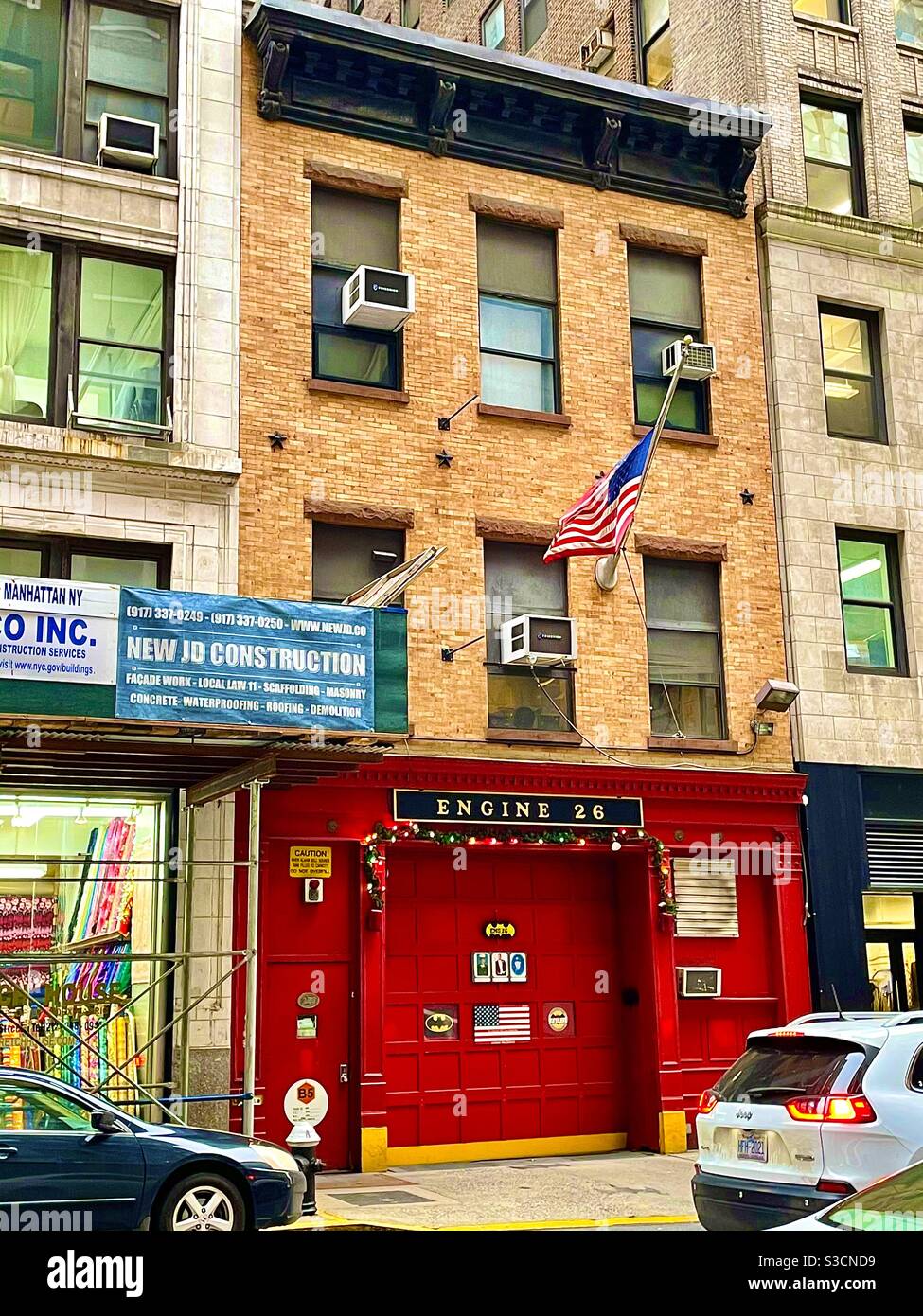 Die leuchtend rote Heimat des New Yorker Feuerwehrmotors 26 in einem bescheidenen braunen Stein eingekeilt zwischen Wolkenkratzern midtown Manhattan ist stolz auf die amerikanische Flagge Stockfoto