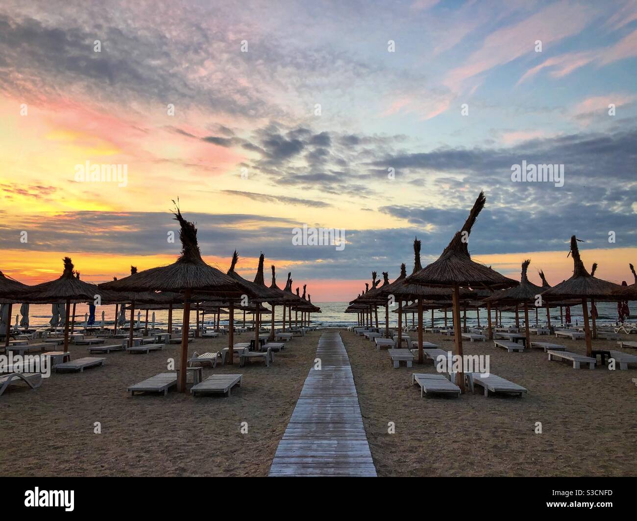 Leerer Strand mit Strohschirmen bei Sonnenaufgang Stockfoto