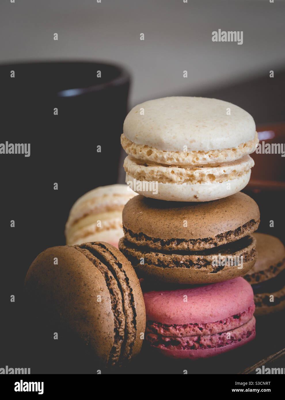 Eine Nahaufnahme von köstlichen und farbenfrohen Makronen mit Schokoladenerdbeere Und Vanillegeschmack und eine Tasse Kaffee für einen Leckere Leckerbissen oder Snacks Stockfoto