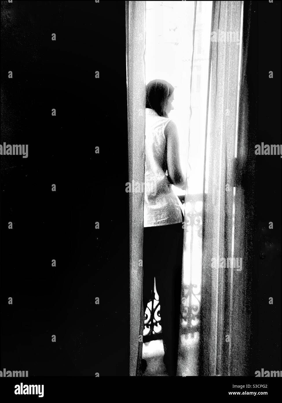 Eine Frau schaut aus einem Hotelzimmerfenster. Stockfoto
