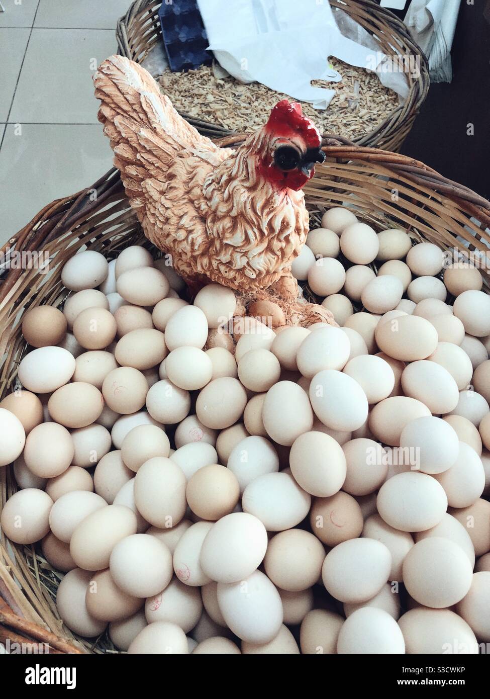 Frische Eier und eine Henne-Figur in einem Korb Stockfoto