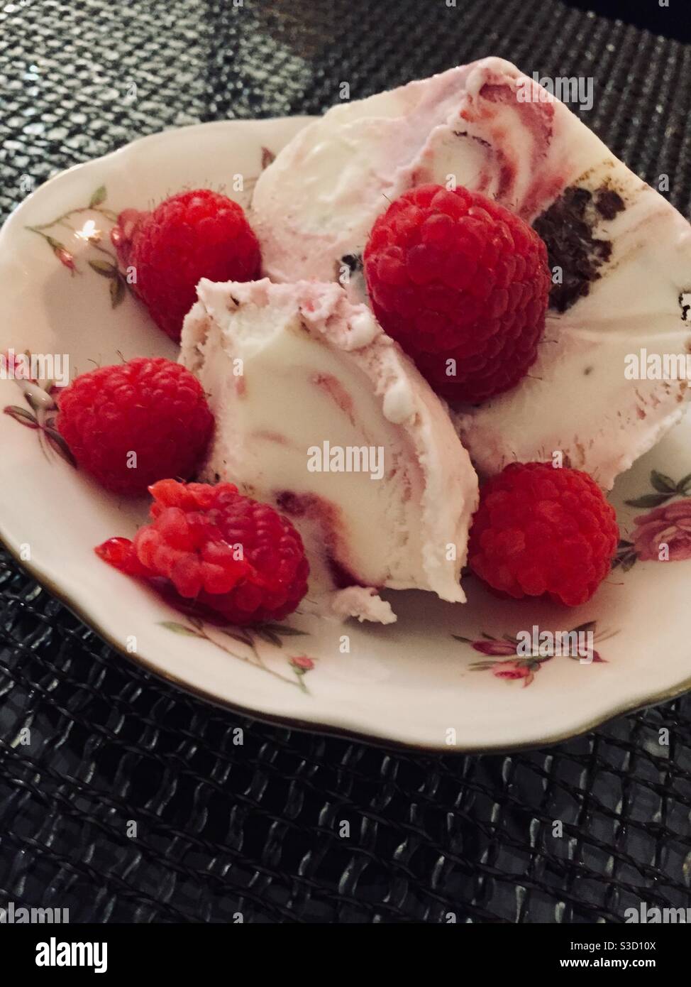 Nahaufnahme eines Eis-Dessert und Himbeeren auf Feines Porzellan - Smartphone-aufgenommenes Stockfoto