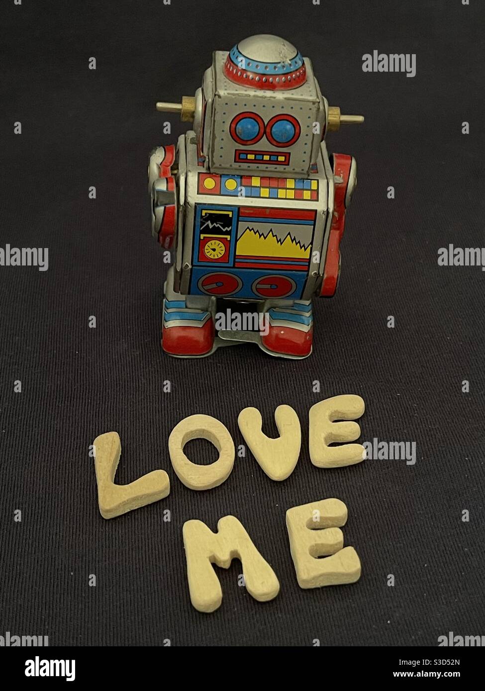 Love Me Text mit Holzbuchstaben und einer Dose komponiert Spielzeugroboter Stockfoto