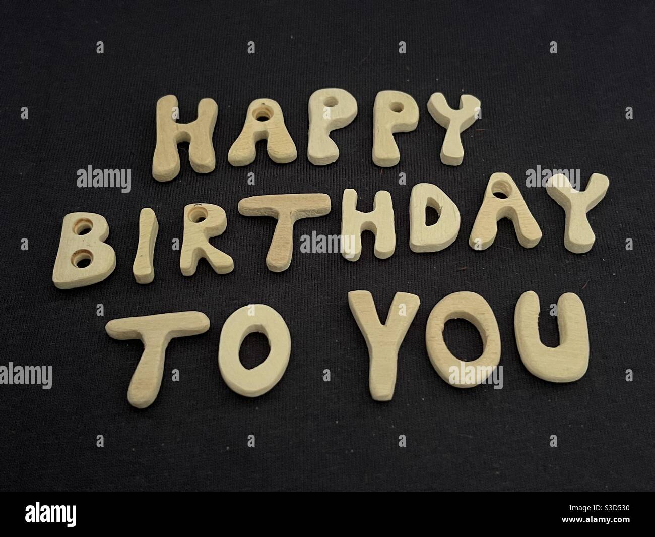 Alles gute zum Geburtstag mit handgefertigten Holzbuchstaben über schwarz Farbiger Hintergrund - Smartphone-aufgenommenes Stockfoto