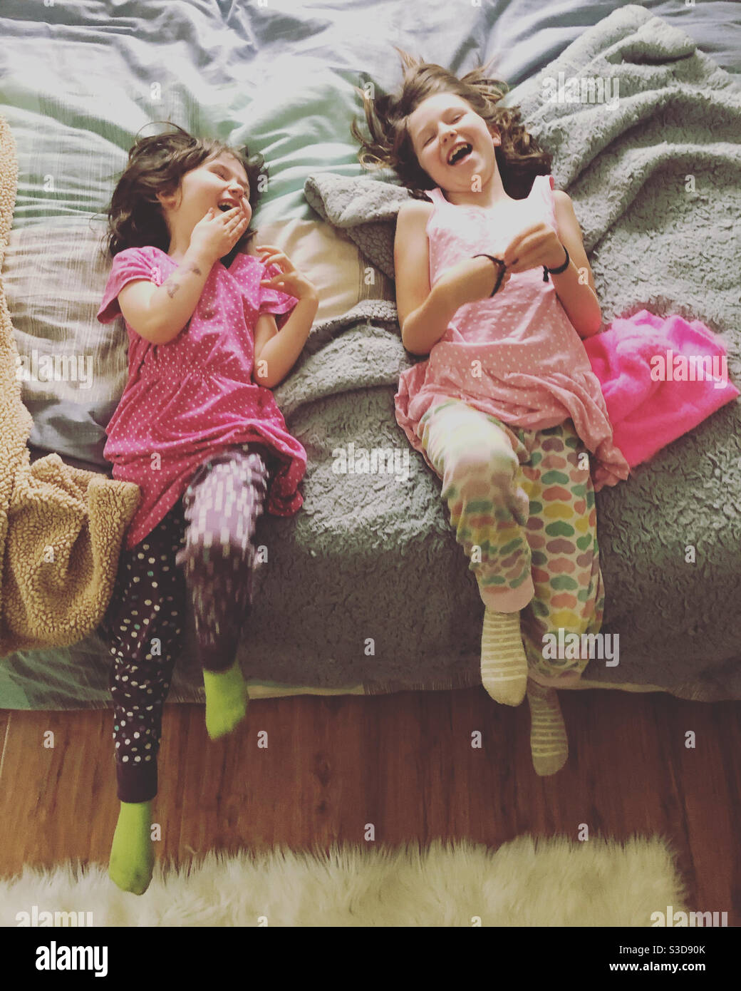 Schwestern lachen im Schlafanzug auf dem Bett. Stockfoto