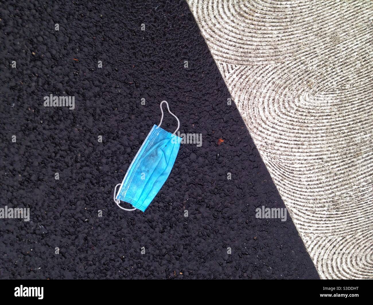 Chirurgische Maske auf der Straße aufgegeben - Smartphone-aufgenommenes Stockfoto