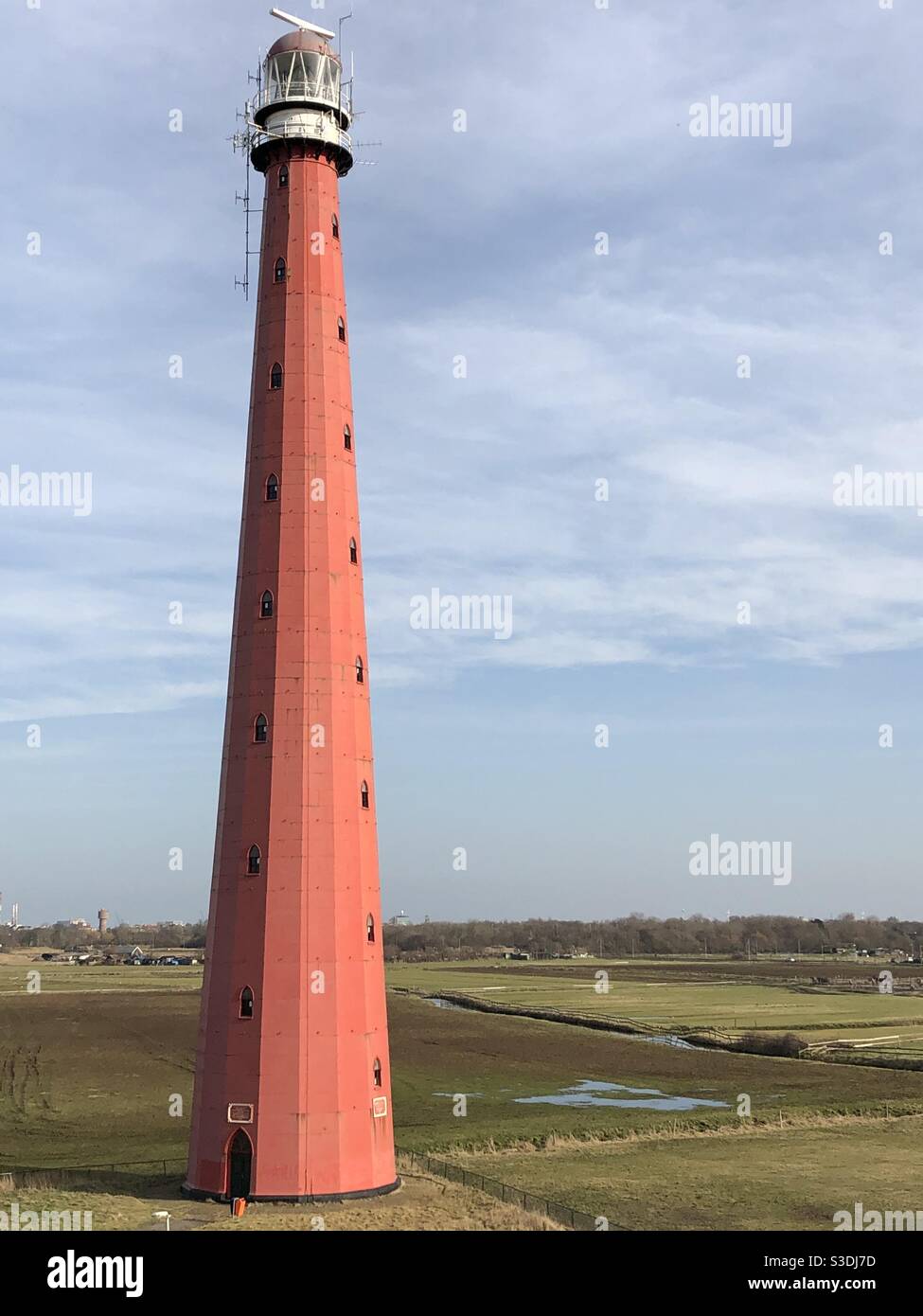 Ein großer roter Leuchtturm, der hinter den Sanddünen sitzt Die Küste in den Niederlanden und mit Blick auf die Nordsee Stockfoto