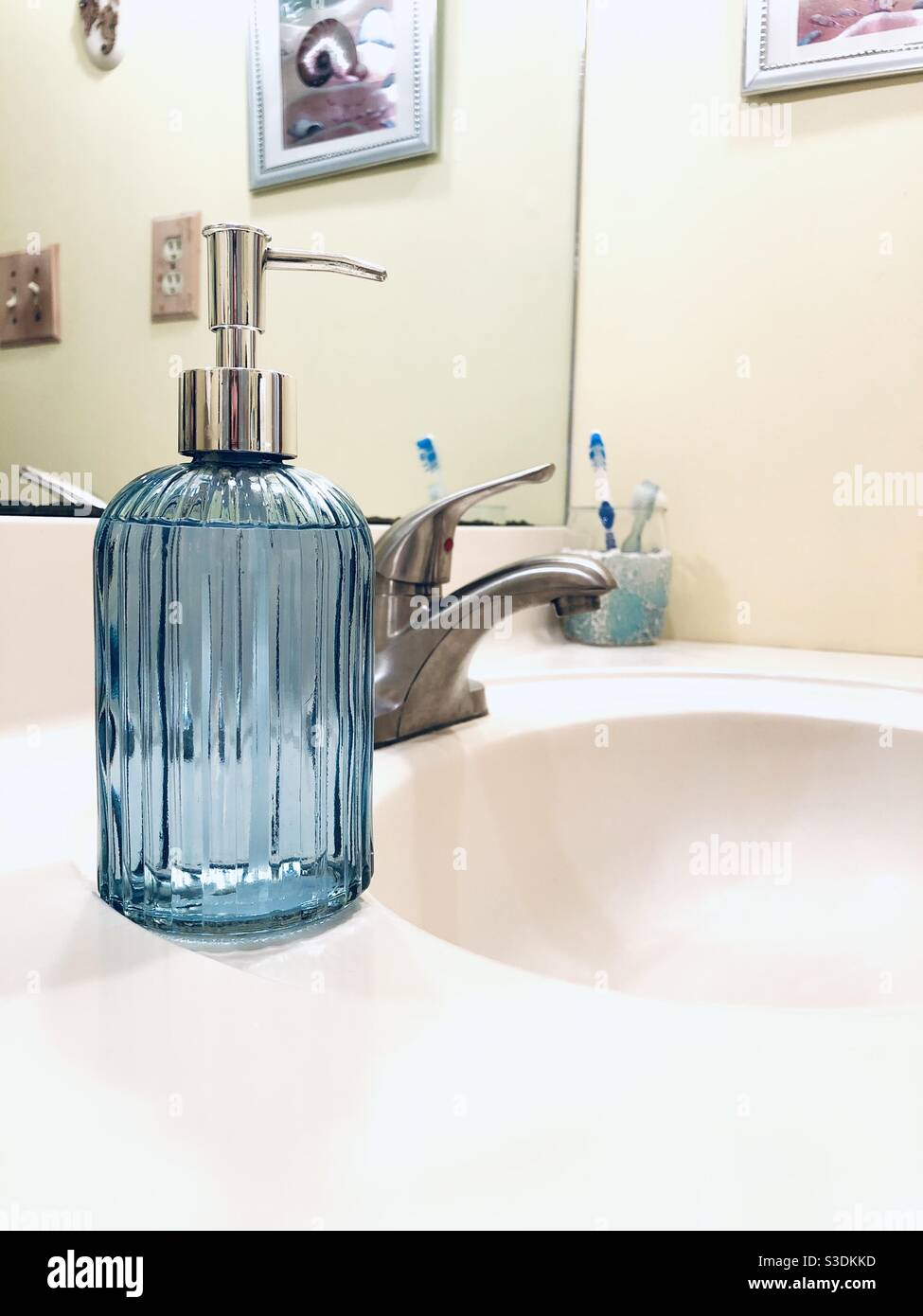 Blauer Seifenspender aus Glas auf dem Badezimmerwaschtisch - Smartphone-aufgenommenes Stockfoto