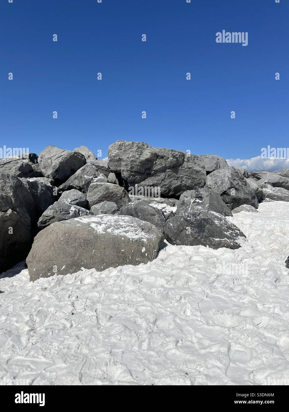Felsige Stege auf weißem Sand Florida Strand mit blauem Himmel - Smartphone-aufgenommenes Stockfoto