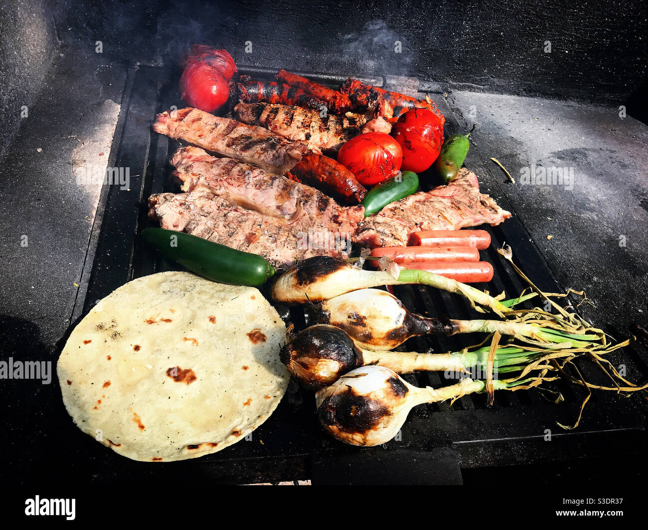Gegrilltes Fleisch, Zwiebeln, Tomaten, Wurst und spanische Chorizo und eine Mais-Tortilla in Araro, Michoacan, Mexiko Stockfoto