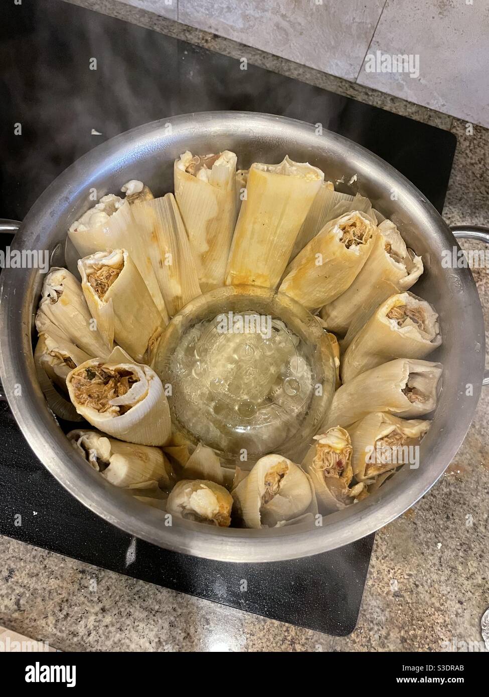 Dampf steigt aus einem Topf mit hausgemachten Tamales Kochen auf Ein Herd Stockfoto