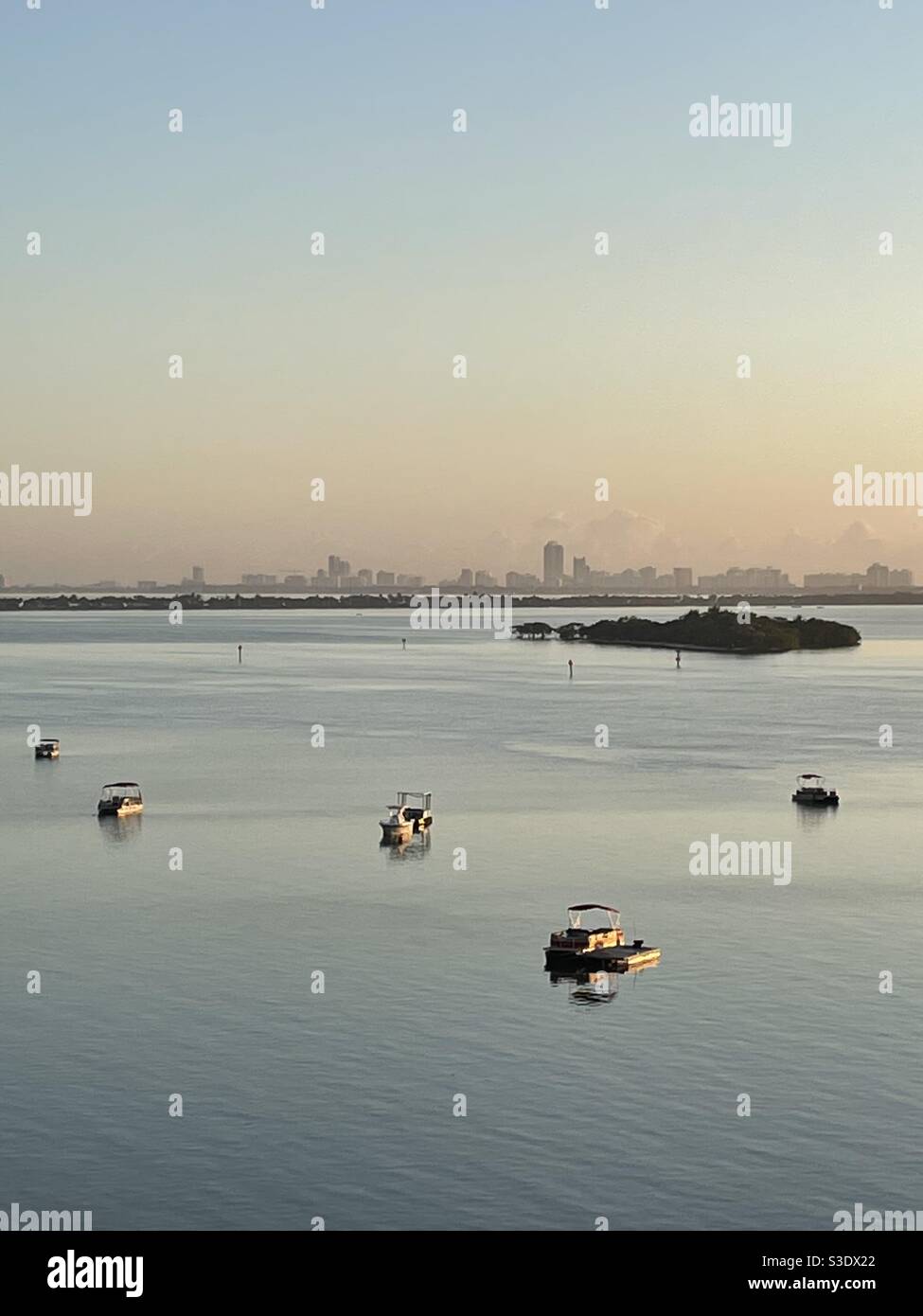 Verschiedene kleine Wasserfahrzeuge auf noch blauem Wasser bei Dawn mit den Gebäuden von Miami Beach im Hintergrund, Florida, USA - Smartphone-aufgenommenes Stockfoto