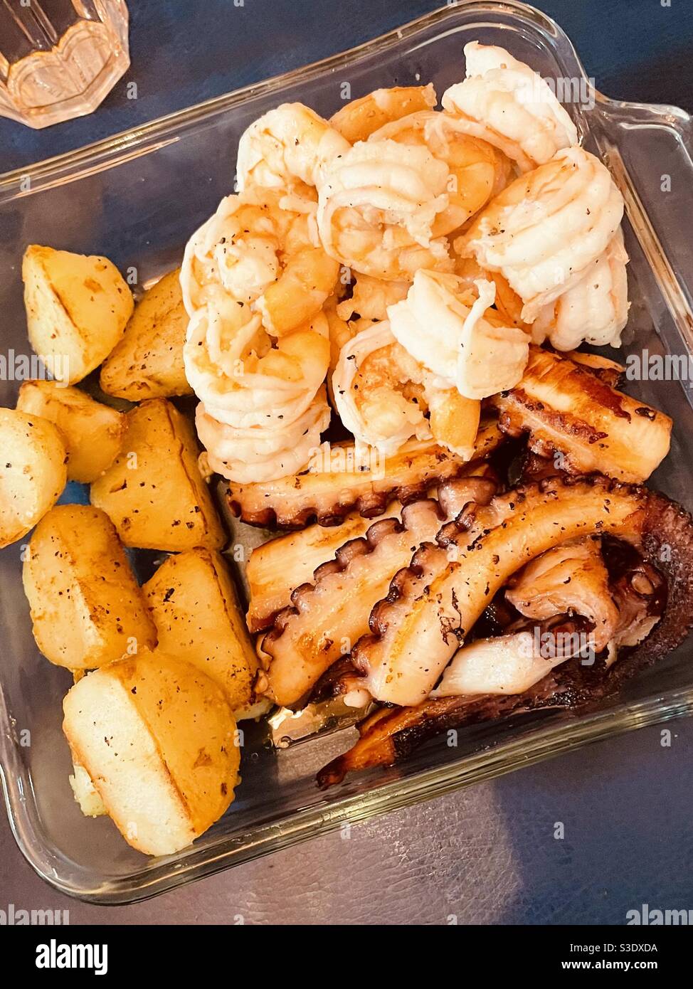 Hausgemachte Vorspeise aus sautierten frischen Jakobsmuscheln, Tintenfisch und Garnelen in einer Glasplatte Stockfoto