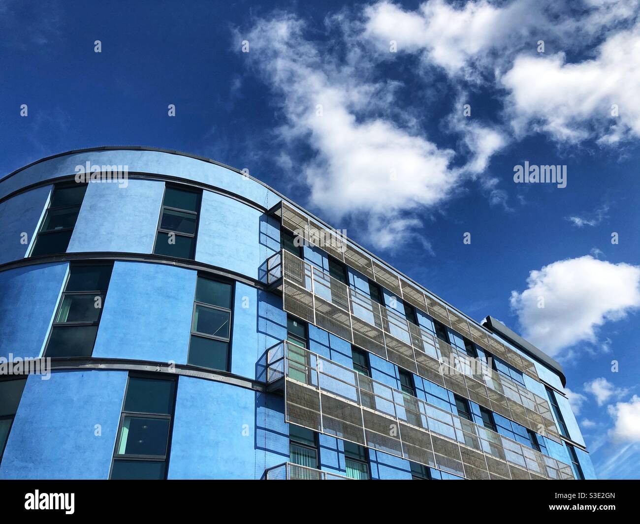Ein farbenfrohes, zeitgenössisches Apartmentgebäude mit geschwungener Fassade, die mit einem bemalten Pastellfarben himmelblau Stockfoto