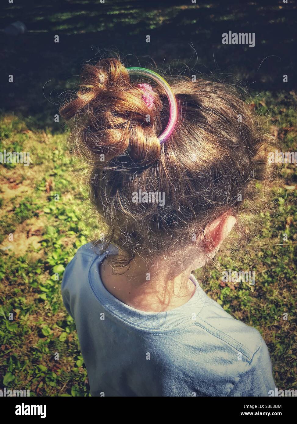 Kleines Mädchen zu Hause gemacht Haar Bun in der Sommersonne Stockfoto