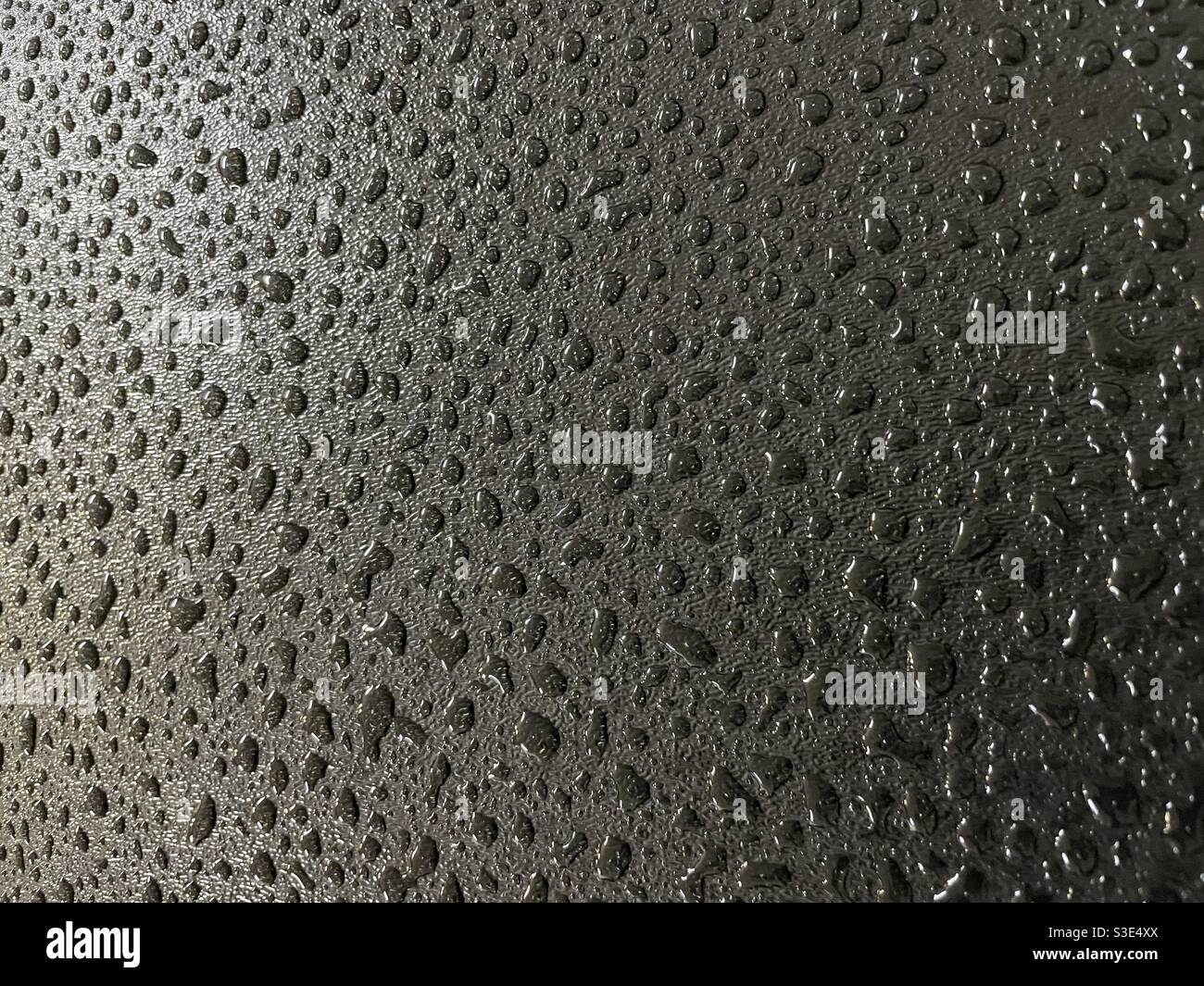 Regentropfen auf schwarzem Hintergrund mit Licht und Schatten - Smartphone-aufgenommenes Stockfoto