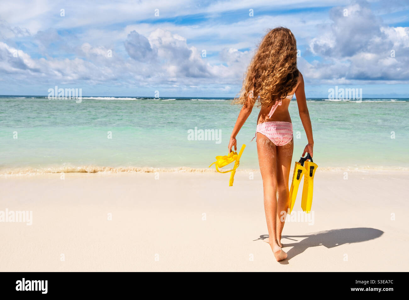 Kleine Schönheit am Meer. Junges Mädchen mit gelbem Schnorcheln, das vom blauen Meerwasser gesetzt wird. Tropisches Sommerkonzept. Stockfoto