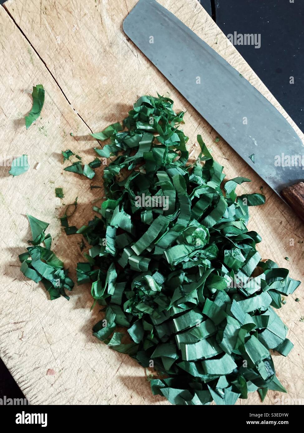 Gehackter Bärlauch auf einem Schneidebrett - Smartphone-aufgenommenes Stockfoto