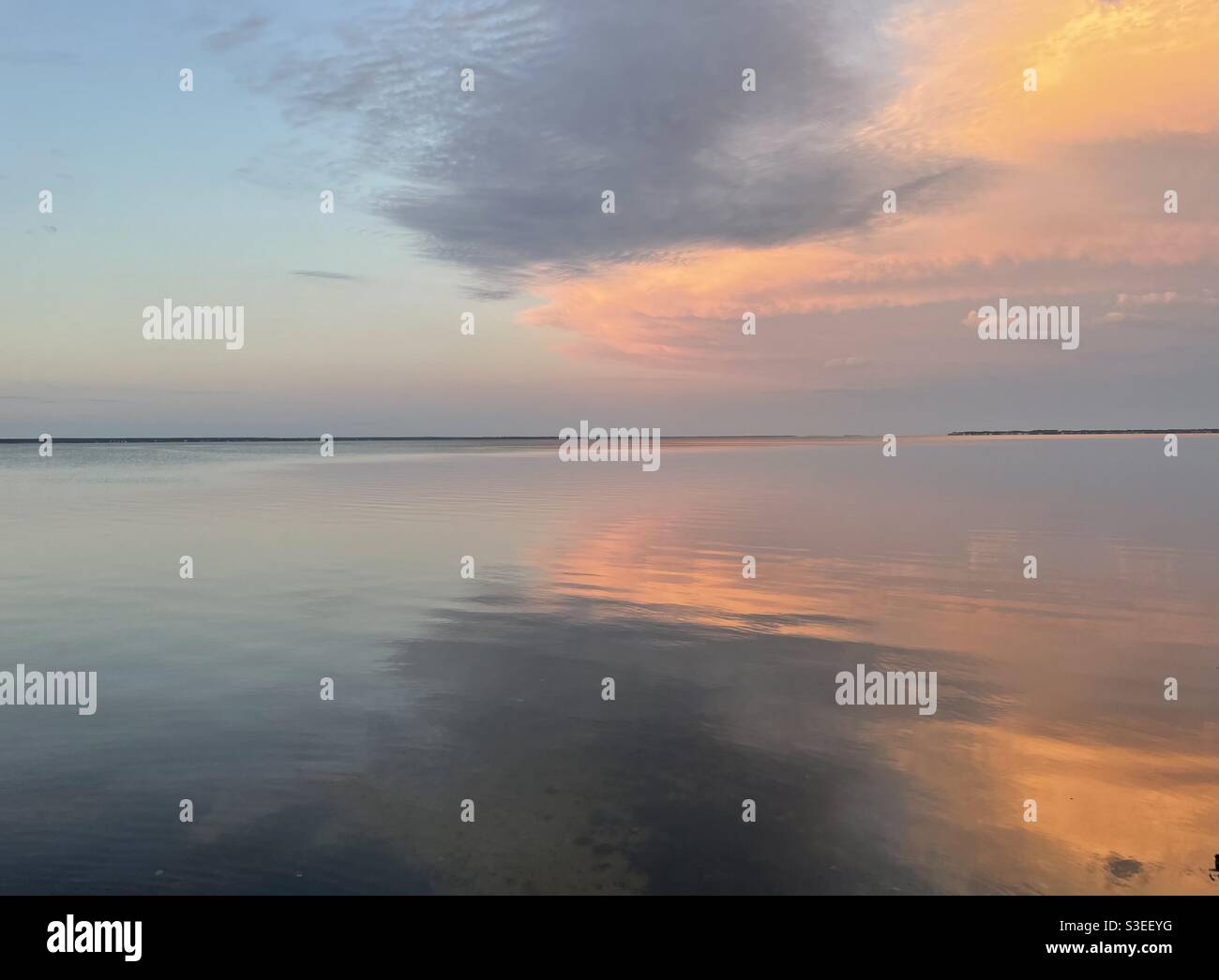Farbenfrohe Sonnenwolken, die sich auf das ruhige Bay Water spiegeln Stockfoto