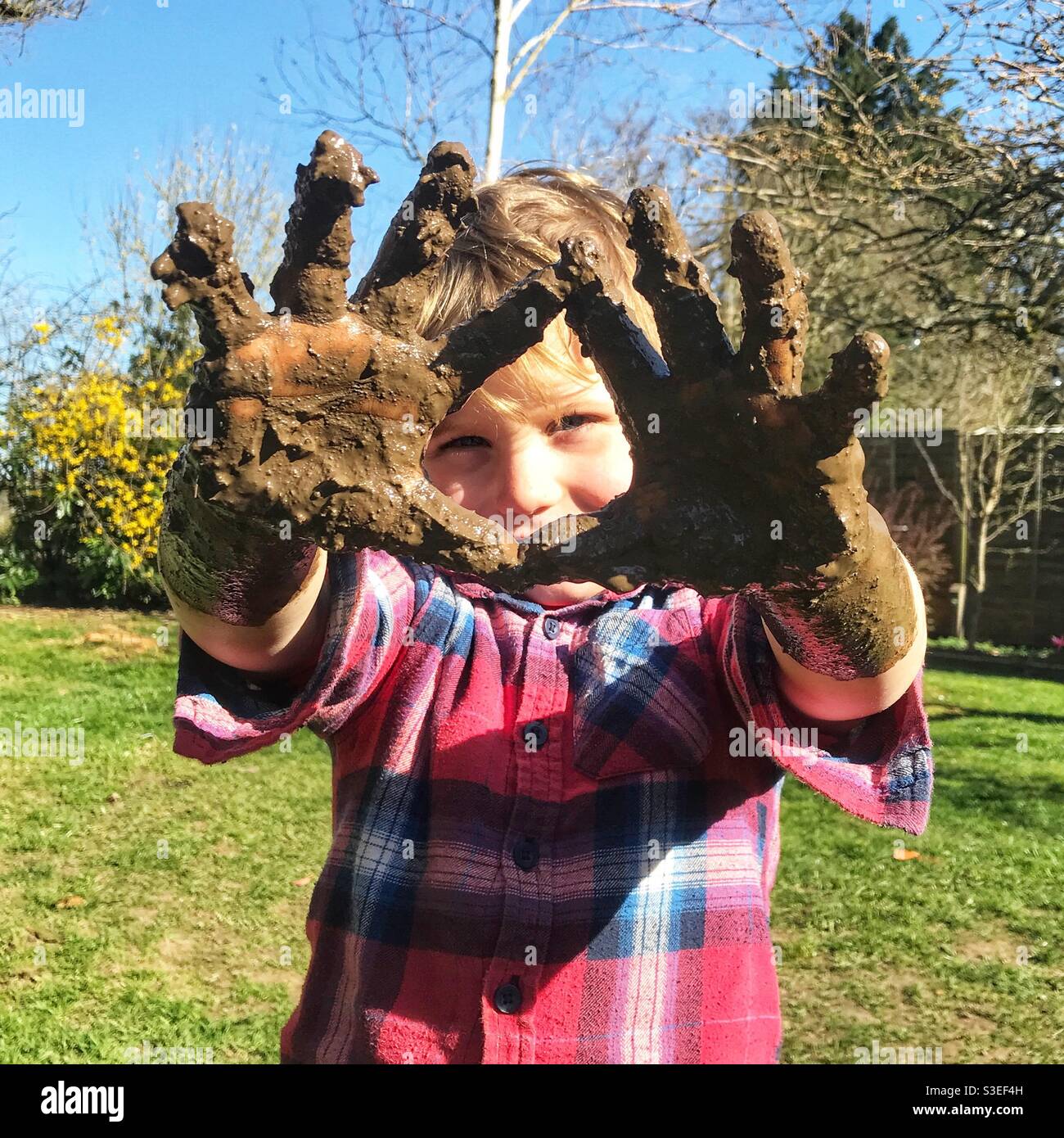 Schlammige Hände. Ein vierjähriger Junge mit Schlamm an den Händen. Stockfoto