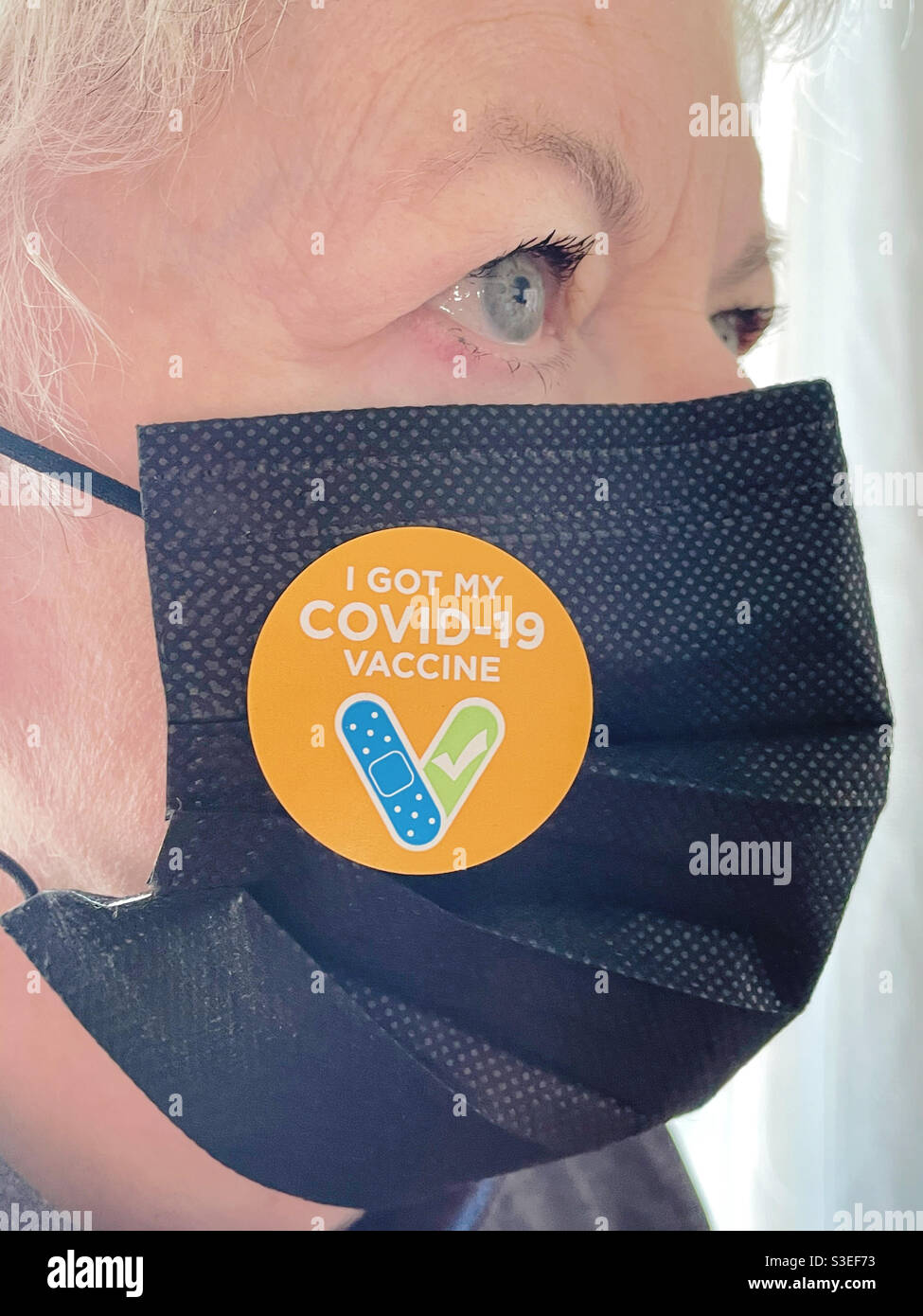 Ältere Frau mit Gesichtsmaske und einem COVID-19-Impfaufkleber, USA, 2021 Stockfoto