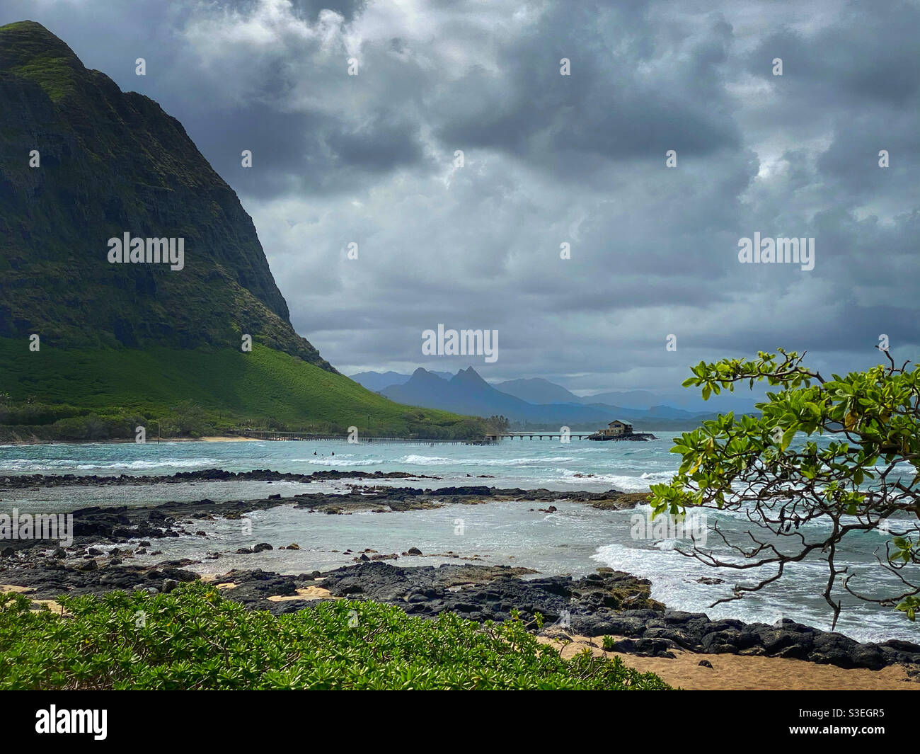 Hawaiianische Landschaft mit einem Haus am Ende eines pier am Fuße eines Berges Stockfoto