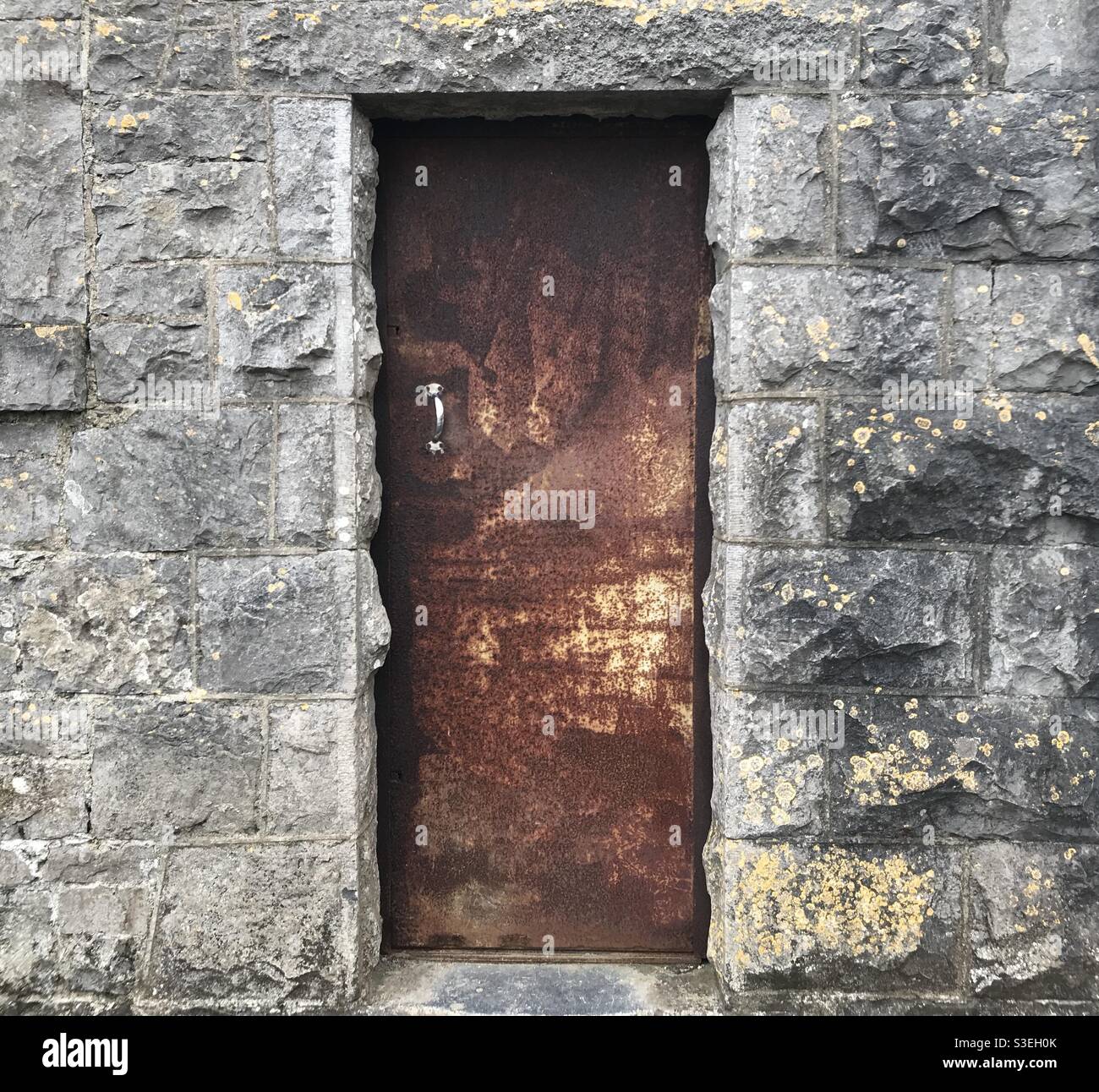 Alte verrostete Tür aus Industriestahl in einem Steingebäude Stockfoto