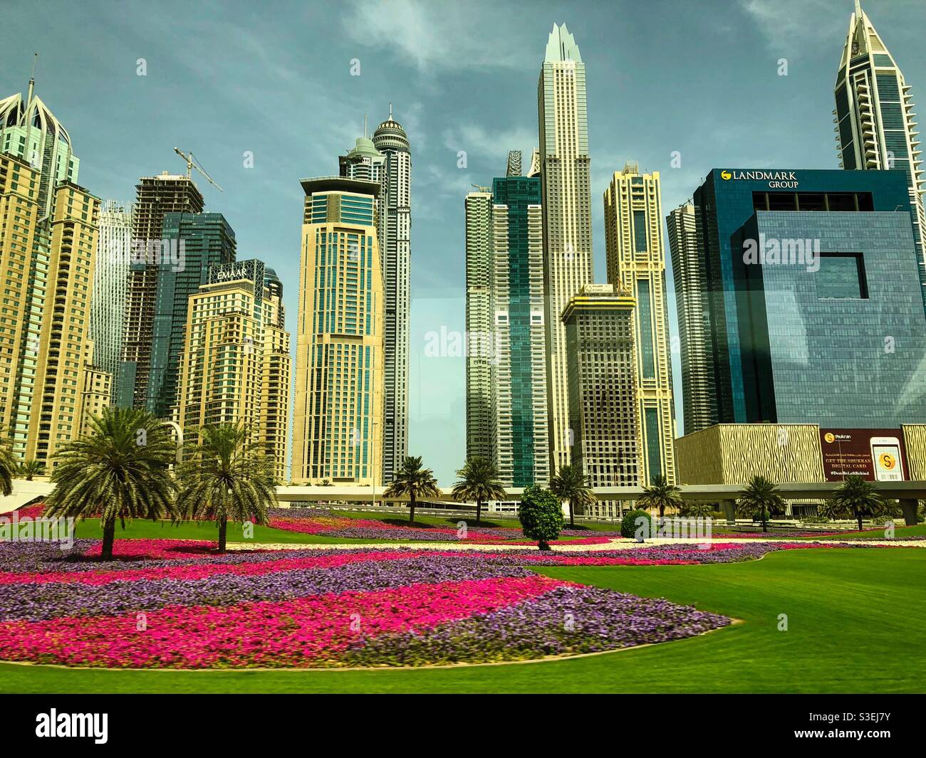Blick von der Dubai Metro auf die modernen Gebäude und Blumen rund um die Sheikh Zayed Road, VAE. - Smartphone-aufgenommenes Stockfoto