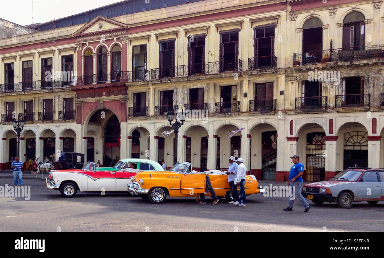 Einheimische Männer mit großen bunten amerikanischen Oldtimern in Havanna, Kuba Stockfoto