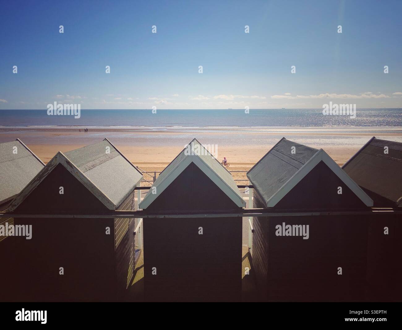 Alte Strandhütten mit Blick auf einen Sandstrand in Großbritannien An einem heißen Sommerferientag am Meer Stockfoto